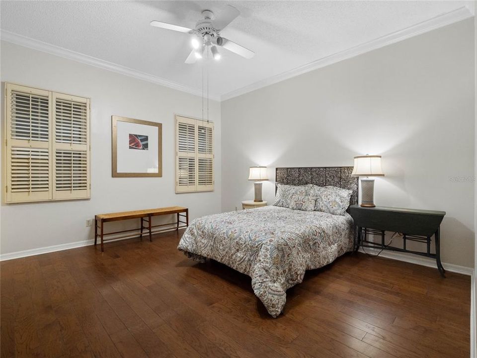Bedroom 2 with wood floors, crown molding, ceiling fan and shutters