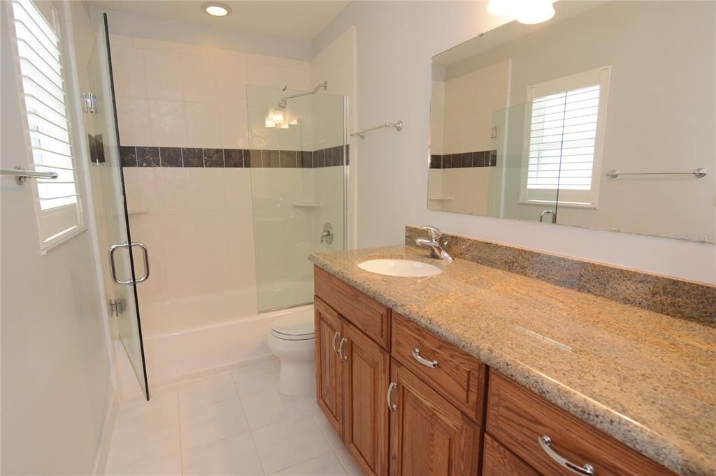 Full bath with an updated vanity, tiled shower with frameless glass door