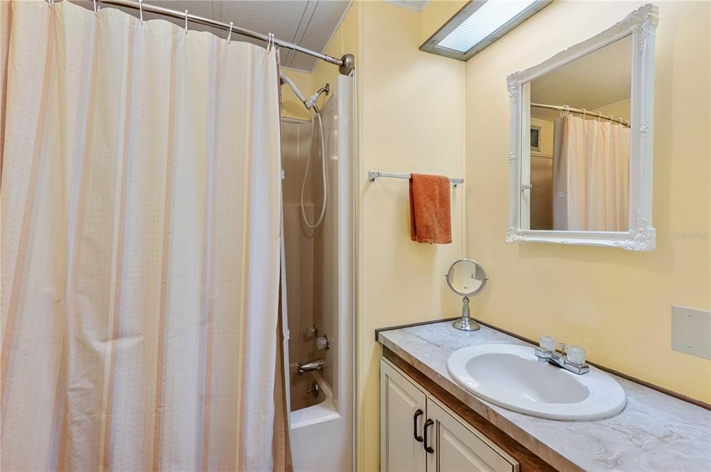 Guest bathroom has tub/shower, updated high toilet, and tile flooring.