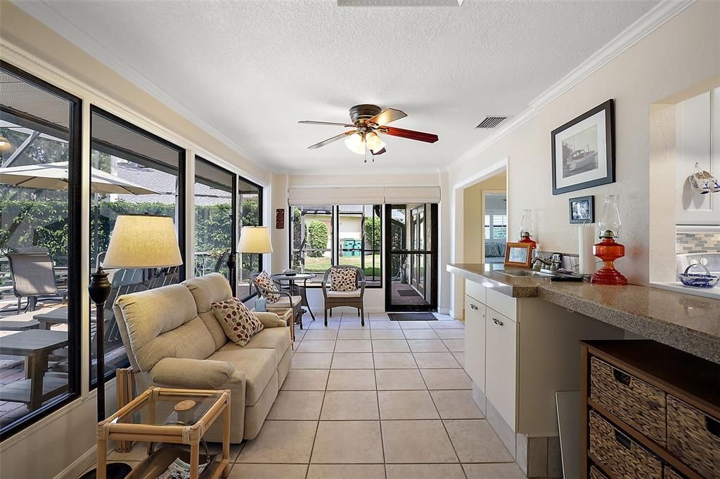 Florida room with large windows overlooking outdoor entertainment area, wet bar