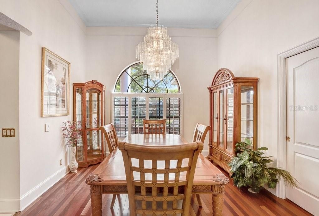 The dining room features hardwood floors, crown molding, plantation shutters, and an elegant crystal chandelier!