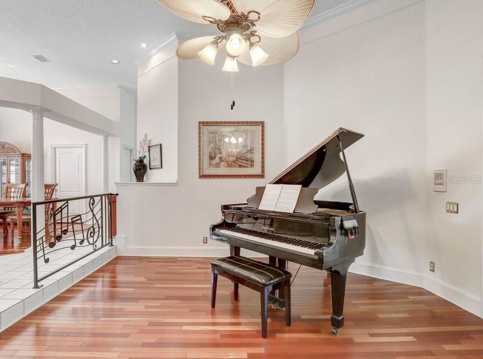 The living room features crown molding, hardwood floors, and a bay grand piano that COULD be yours!  Check out the wrought iron railing!