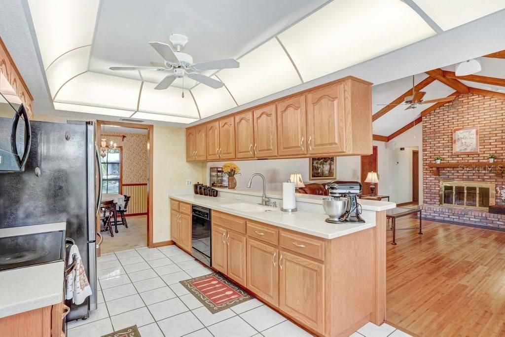 The kitchen has solid wood cabinets, solid surface countertops,  black appliances, and a breakfast bar that seats 4 stools.