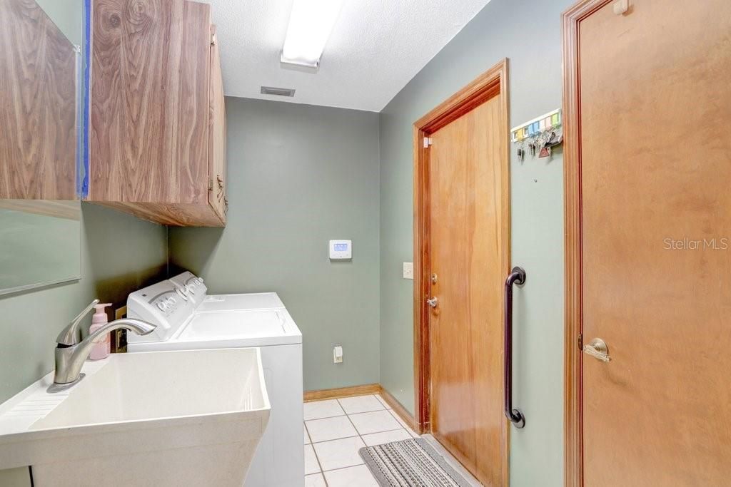 The laundry room features overhead cabinets, a closet pantry, and a utility sink.
