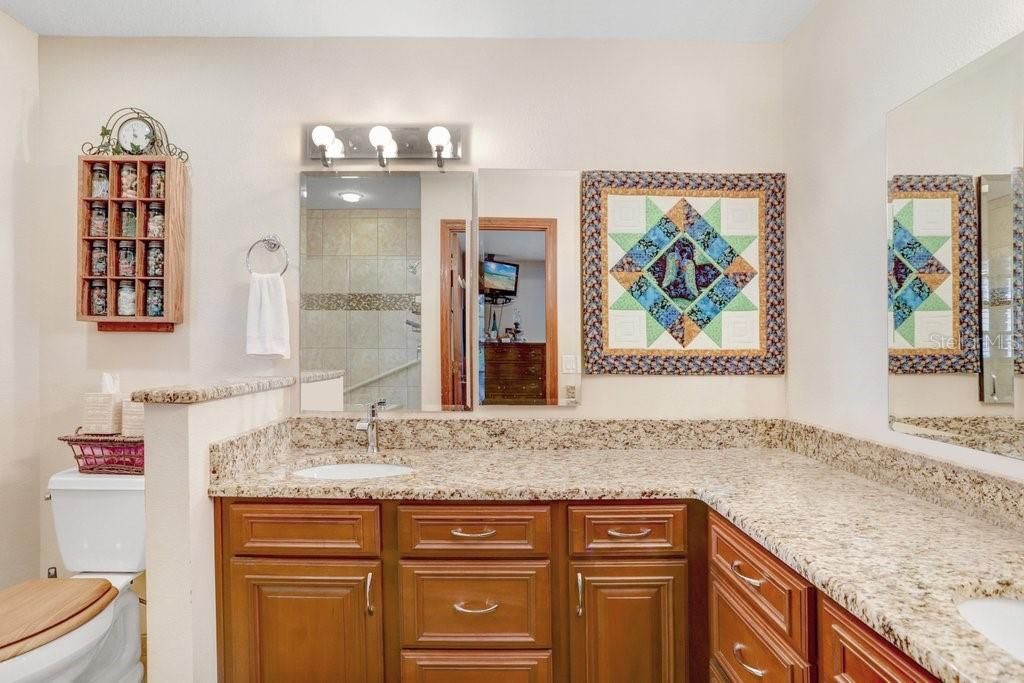 The updated master ensuite features dual sinks, granite countertops, solid wood cabinets, updated lighting, and a frameless walk-in shower.