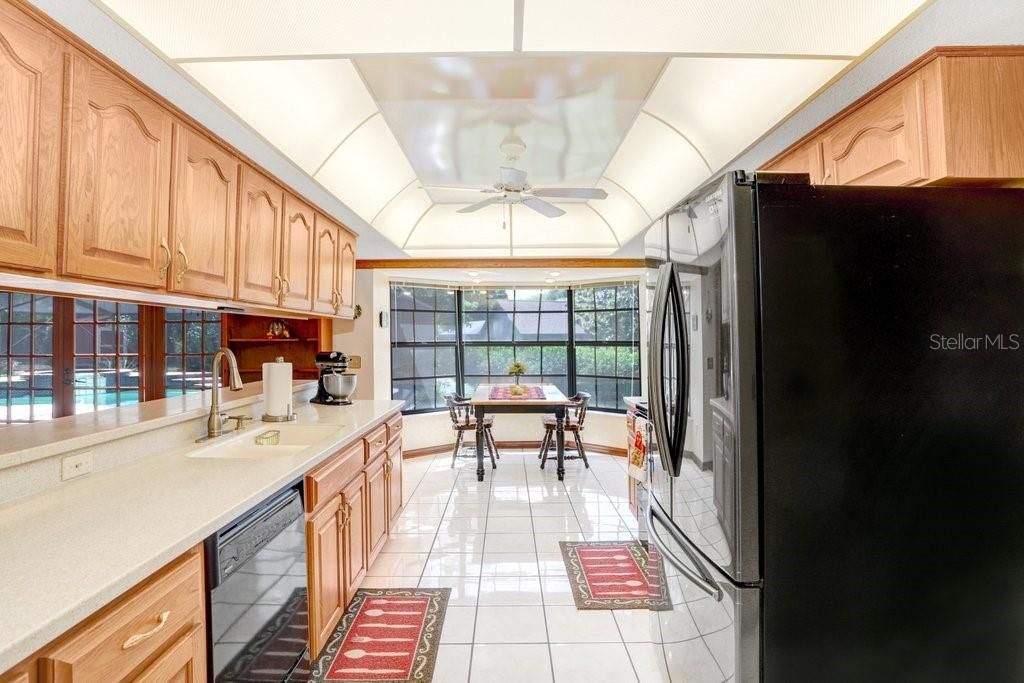 The kitchen has solid wood cabinets, solid surface countertops, black appliances, and a dinette with a bay window.