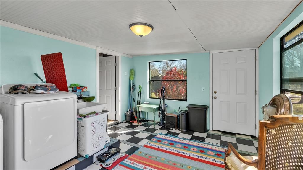 Utility room for laundry units and sink with door leading outside