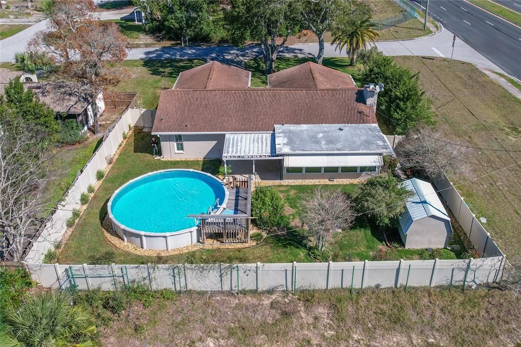 Aerial view of back of the home, above ground pool and deck, large shed, all surrounded by the vinyal privacy fence.