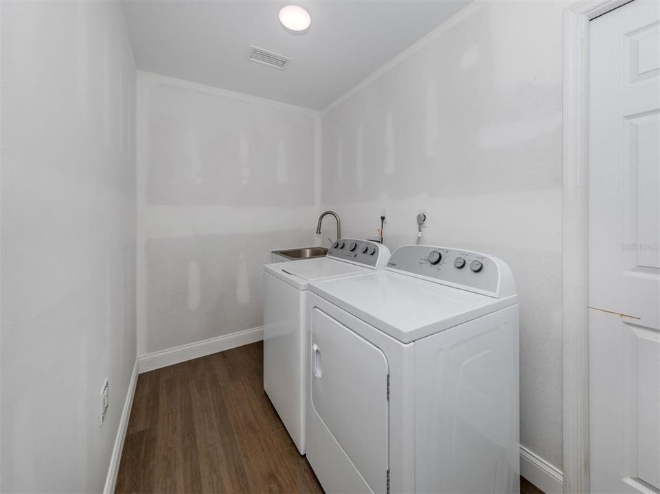 The laundry room is conveniently located inside of the home, so it is air conditioned! There is a large laundry sink/tub. Washer and Dryer are included. Extra storage space (not seen in this photo). Enter the laundry room from the garage. The door shown leads to a small hallway and the kitchen area.