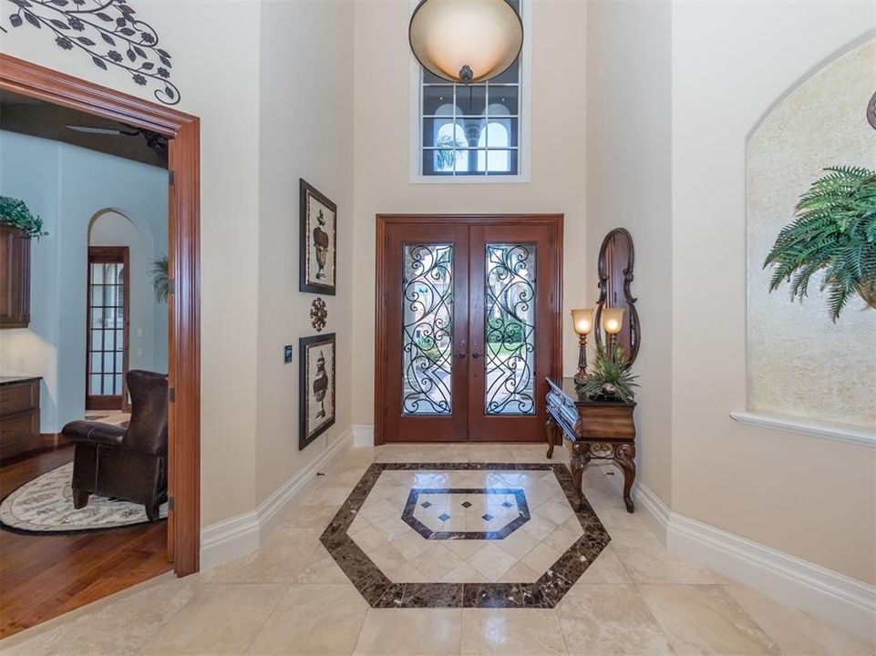 Foyer with iron and wood front doors and tile inlay