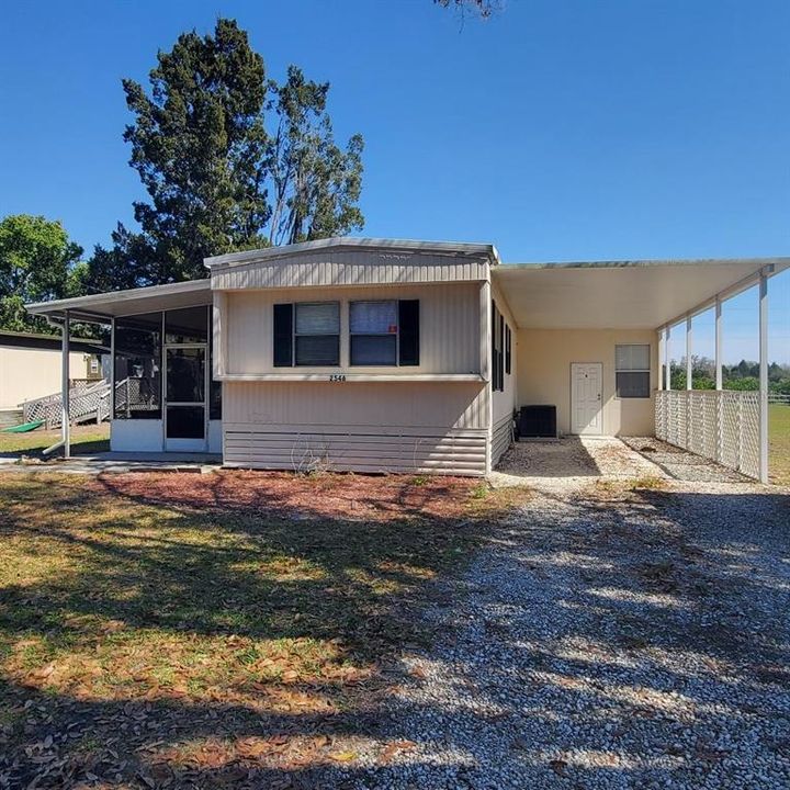 Front with covered screen porch and covered carport - plus driveway