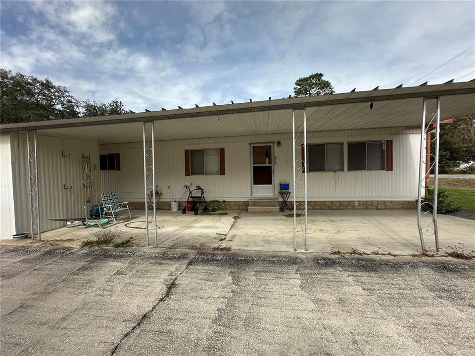 Long carport with main entrance, extra paved parking area