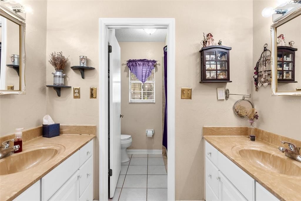 Dual Vanities lead to separate Water Closet with Jetted Tub with Shower Combo