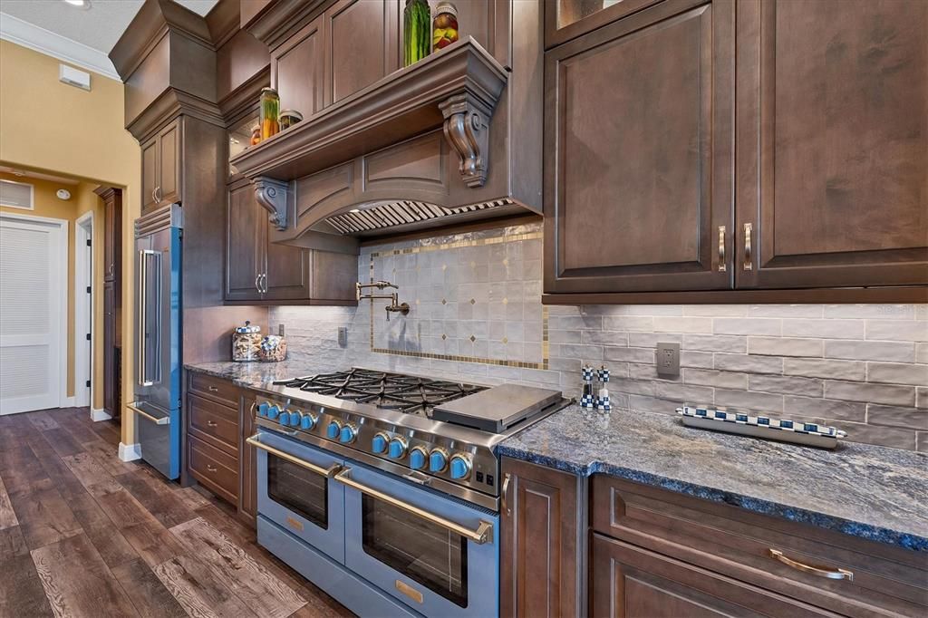 Matching BlueStar French door "Pigeon Blue" Refrigerator w/ Brass trim and 60' Double Ovens w/ 10 burner range w/ Brass trim AND Brizo Pot Filler ... Brass colored accent tile in the backsplash... WOW!