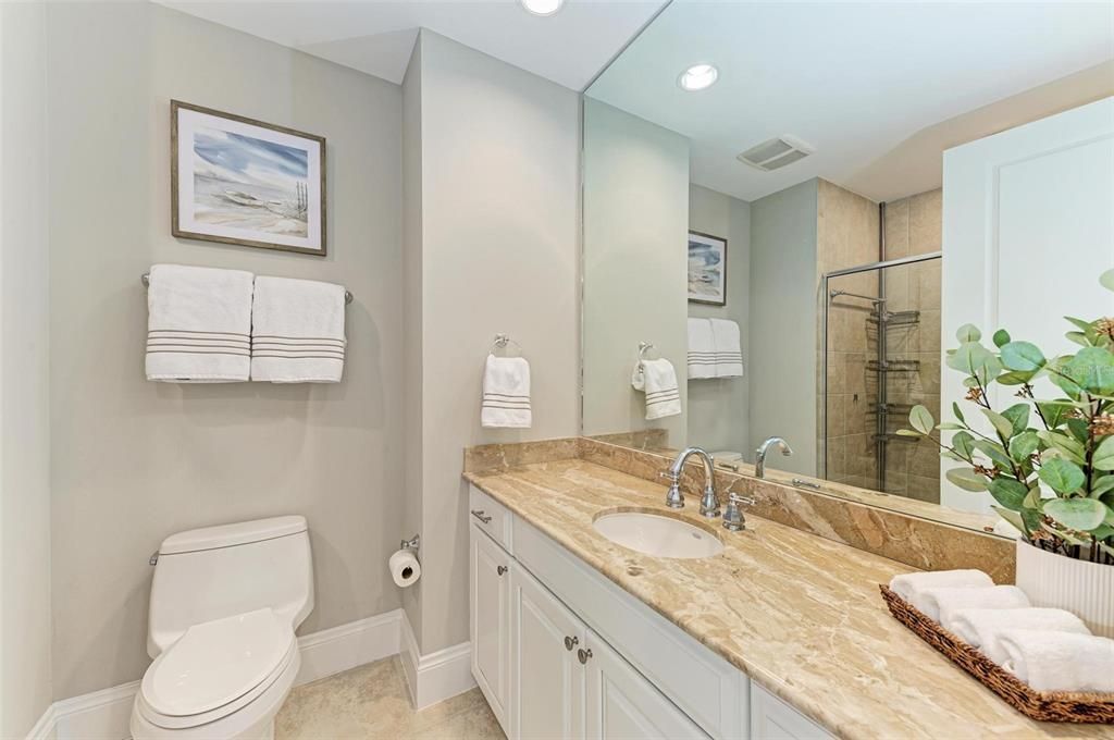 Guest bath with solid wood Masterpiece dovetail cabinetry, marble countertops, and walk in shower.