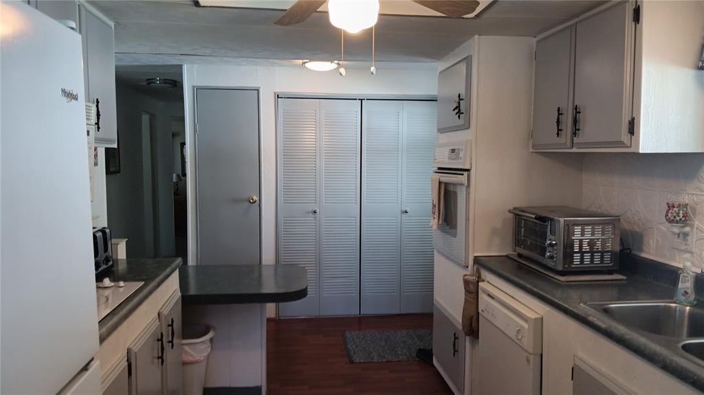 Galley Kitchen with Pantry Closet, Large Utility Closet, Cooktop, Built In Oven, Dishwasher, Microwave, Refrigerator and Breakfast Bar.