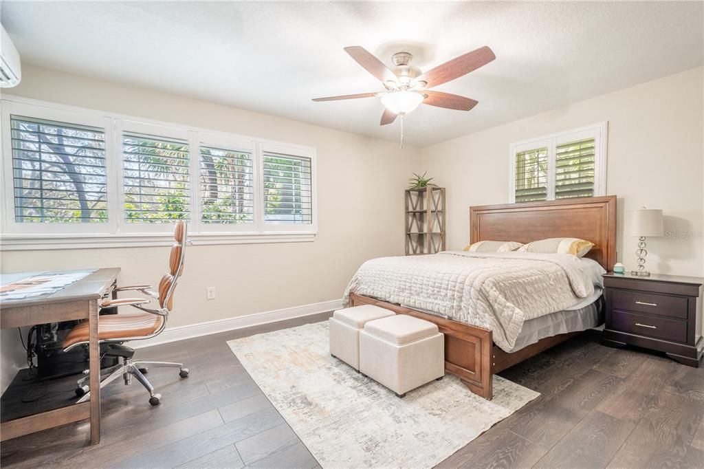 The first floor primary bedroom features wood laminate flooring, a ceiling fan, plantation shutters and a ensuite bath.