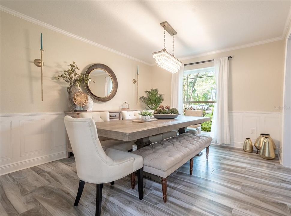 The dining room features a floor to ceiling window and a stunning, modern chandelier.