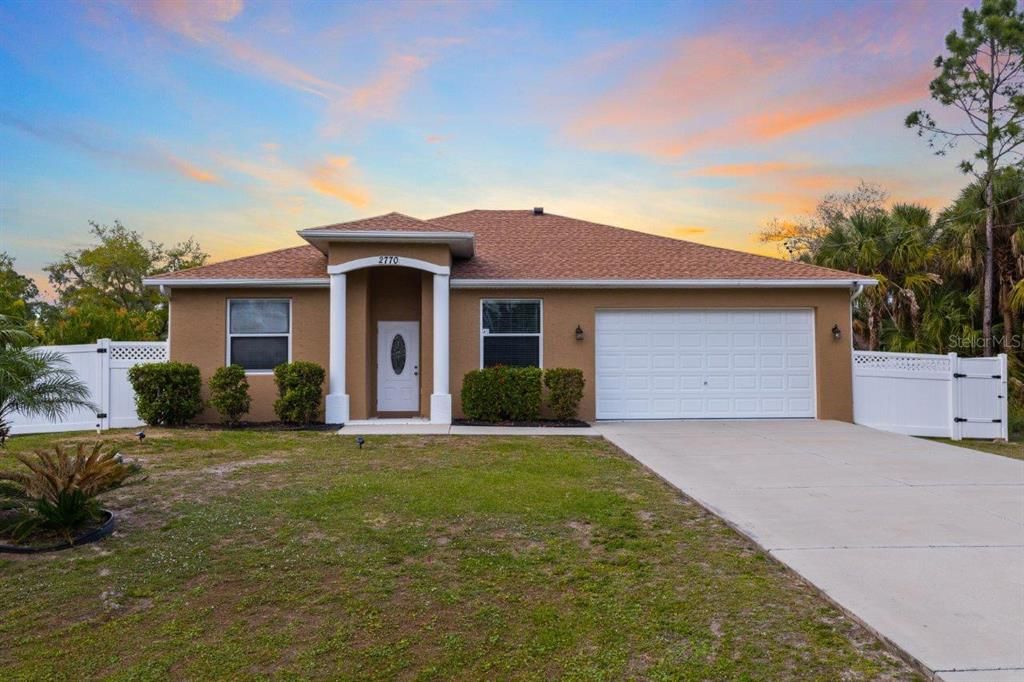 Front elevation showing the over sized driveway, NEW Roof, front entryway, NEW fence, and a fresh coat of paint.