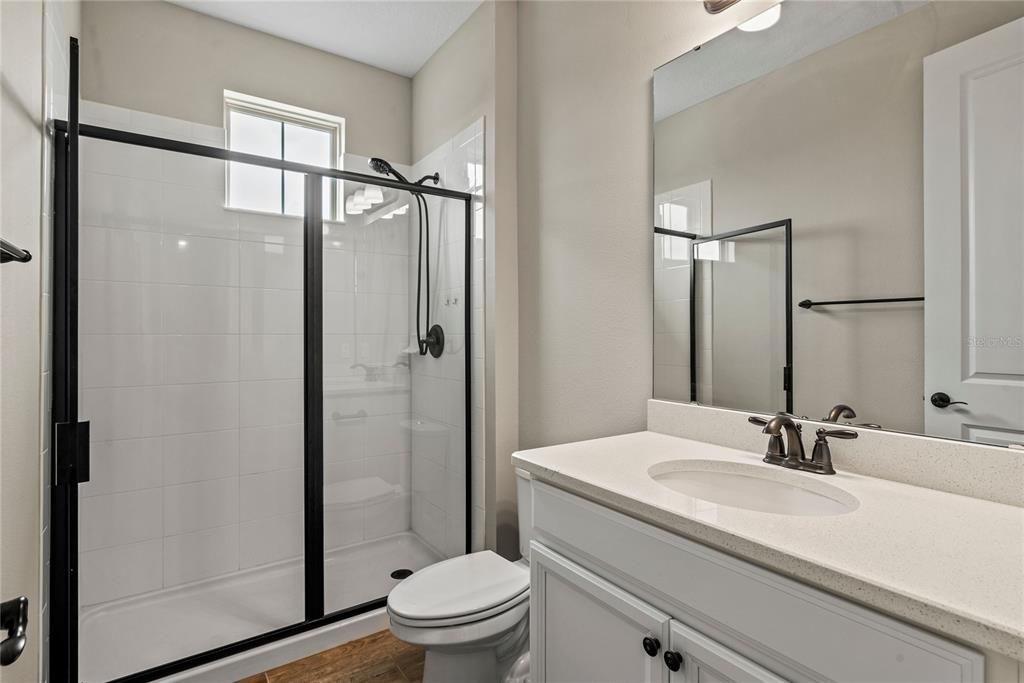 Hall bath situated between Bedroom 4 and Bedroom 5 with granite vanity and glass enclosed tile shower