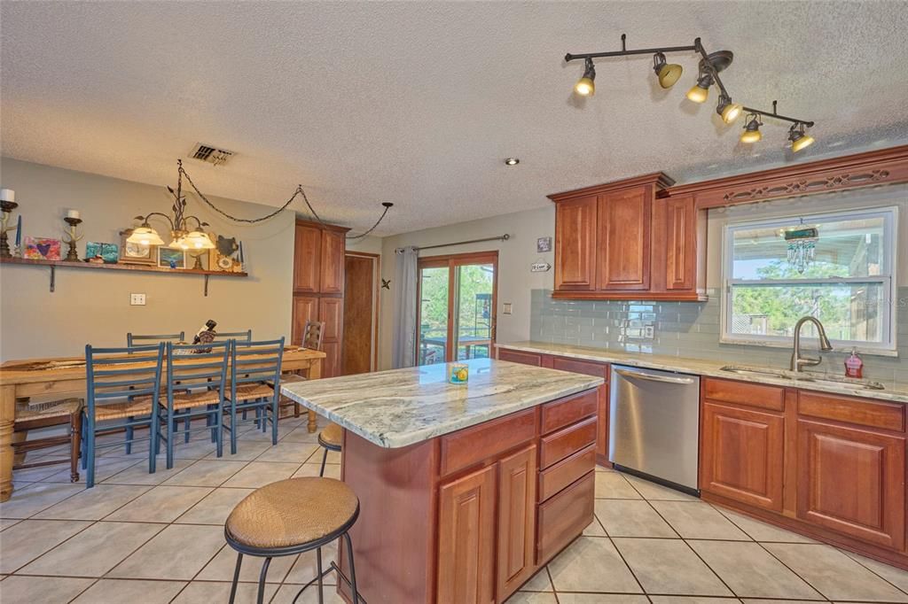 Kitchen with view of dining area.  Doorway in back leads to laundry room.  Double doors open out to patio/porch area.
