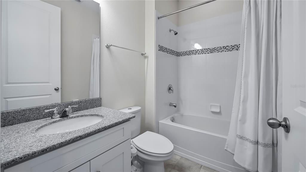 Bathroom 3 with granite countertops, linen closet (in hall), and tub and shower combo.