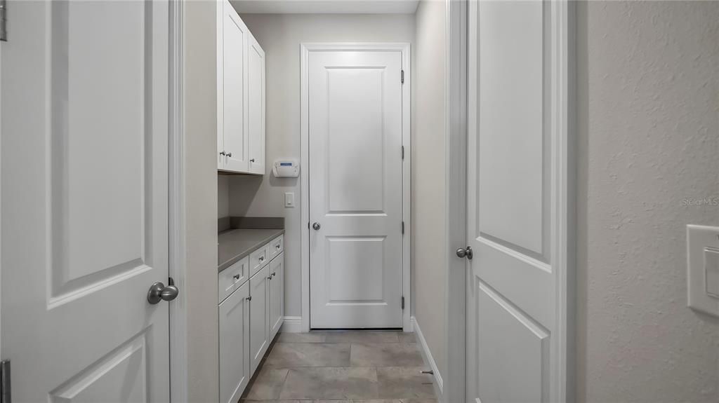 Door from garage with laundry room, storage closet and cabinets.