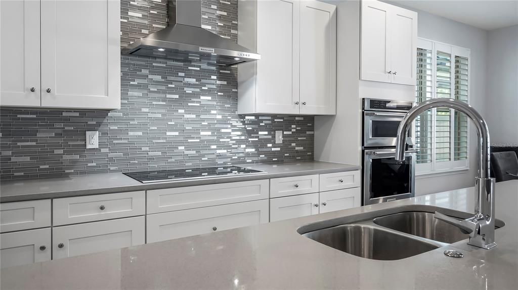 Kitchen with large center island, breakfast bar, walk-in pantry, eat-in breakfast nook, stainless steel appliances, quartz countertops, and custom back splash.