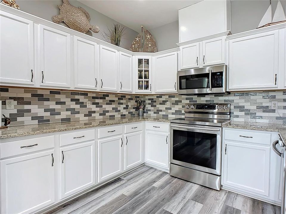 Gorgeous kitchen with a beautiful backsplash, stainless steel appliances and inviting granite countertops.