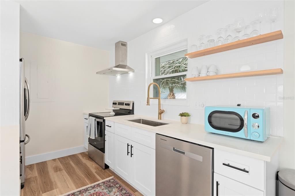 Brand new kitchen with stainless steel appliances, white cabinets, quartz countertops, gold faucet, floating shelves.