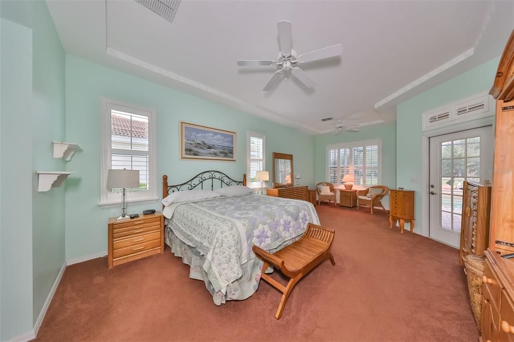 The primary bedroom is HUGE with soft coastal paint tones, ceiling fans, plantation shutters, an extra sitting area and hurricane impact windows.  A door leads onto the lanai for those evening swims!