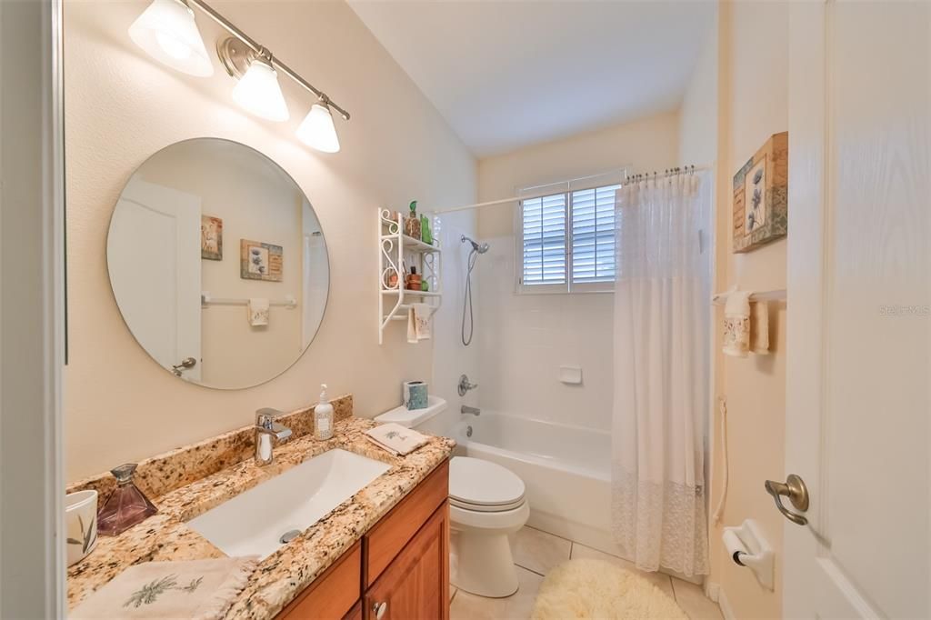 Updated classy guest bathroom with granite countertops and matching tile floors.
