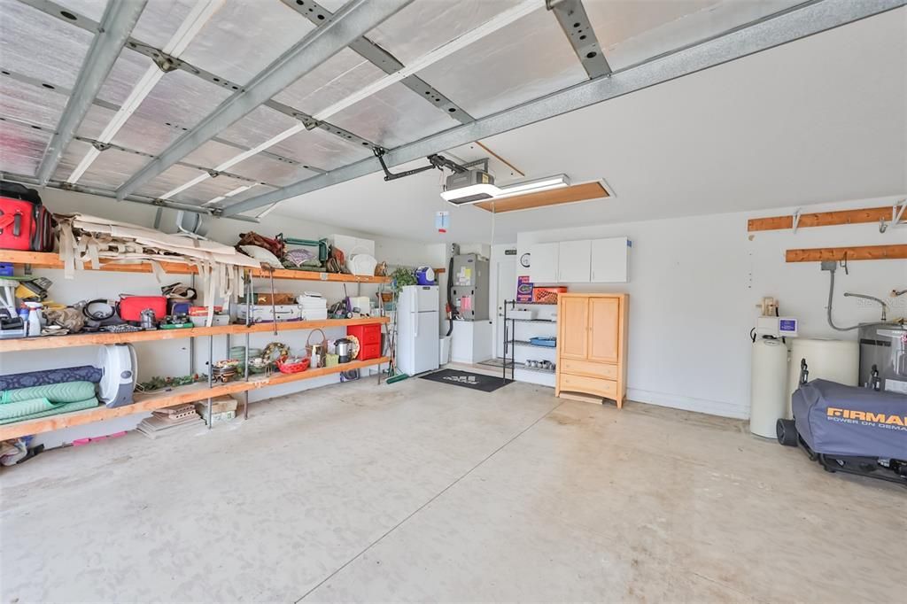 Ample space with wall storage, insulated garage door, and pulled down attic stairs in this two-car garage.