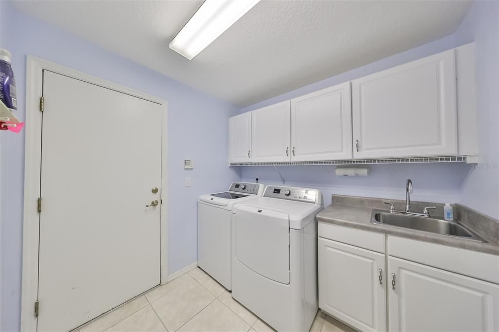 An indoor laundry room offers lots of extra storage, bright lights and a utility sink.
