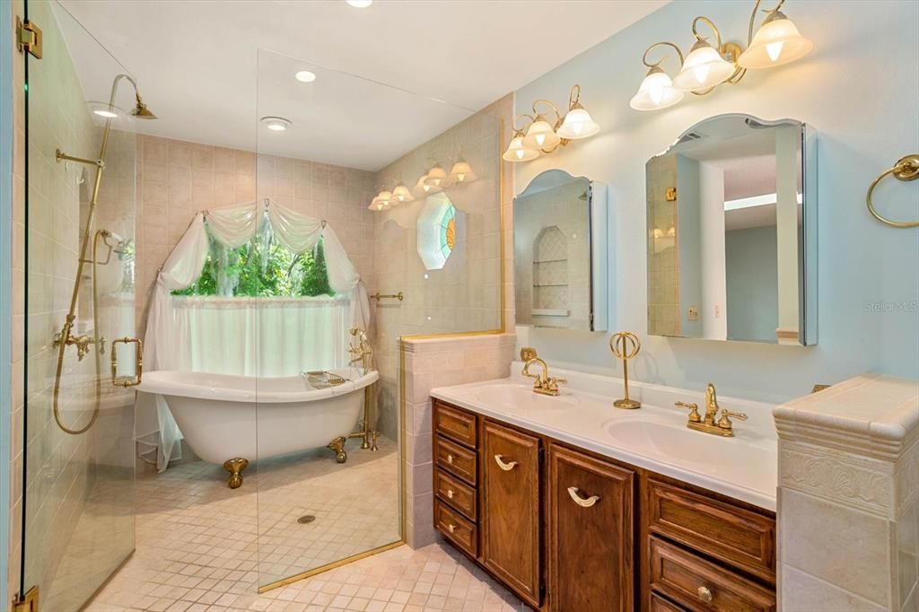 Stylish glass enclosed SHOWER WITH CLAW FOOT TUB AND SPLIT DOUBLE VANITIES give the feel of a spa vacation getaway.