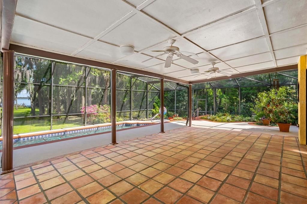 Huge main covered porch features beautiful tiled floors, ceiling fans and pool to lake views.