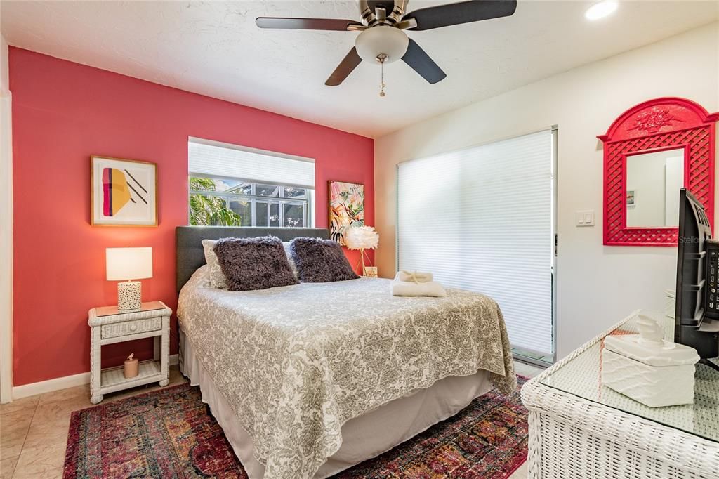 Bedroom 2 with doors to pool area and overhead fan