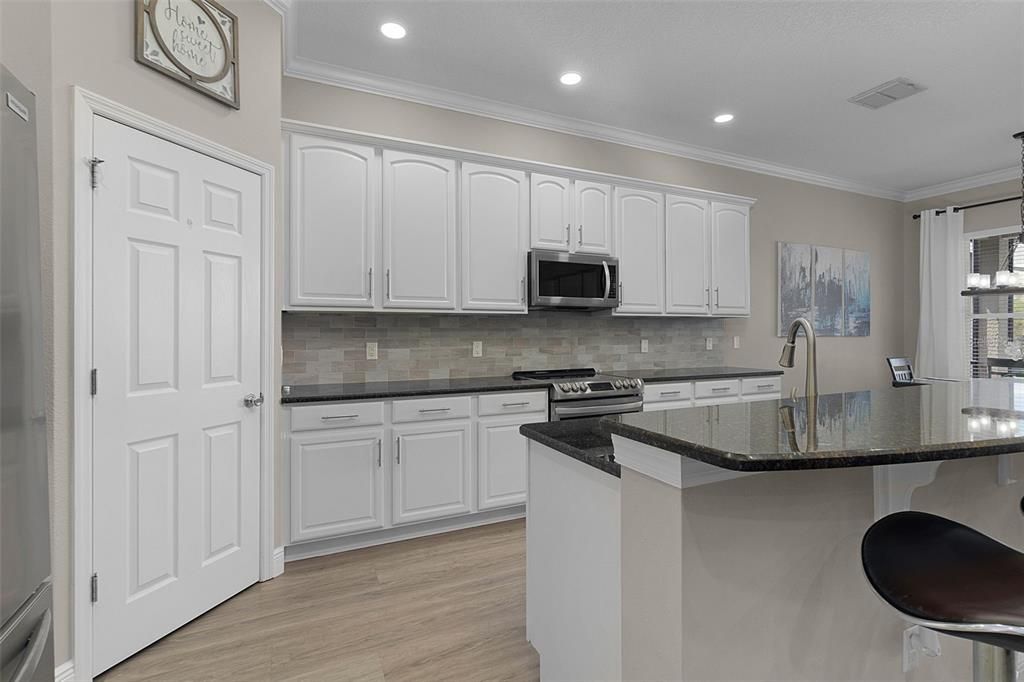Freshly painted cabinets, stylish pulls, a tile backsplash, and granite countertops make for an exquisite cooking experience