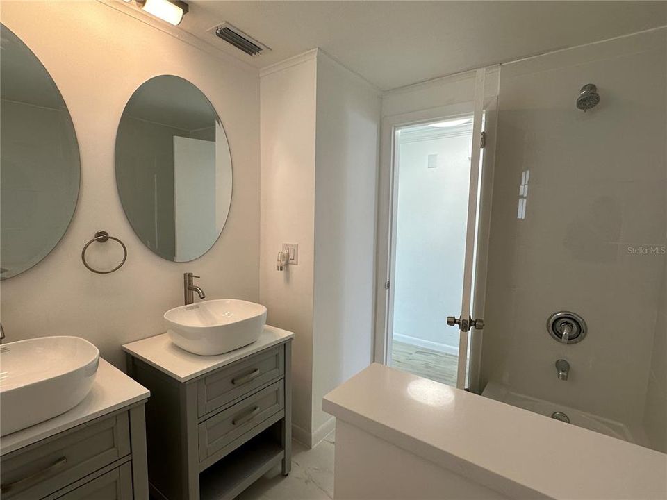 Guest bathroom with dual sinks and bath tub.