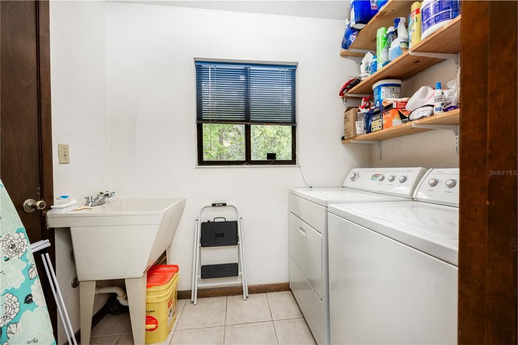 Laundry room with washer and dryer, laundry tub and shelving for storage