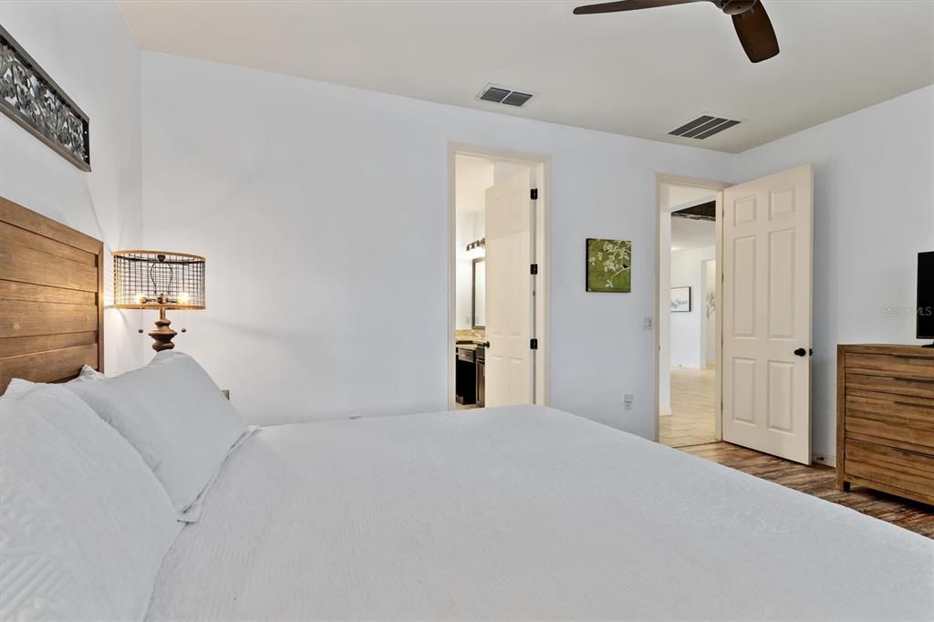 Primary bedroom with view towards ensuite bath and hallway leading to living and family rooms.