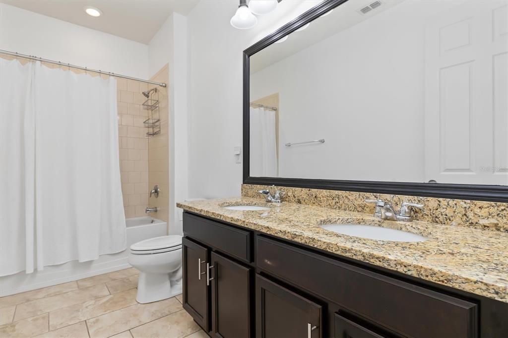 Guest bathroom features tub and shower combination plus a dual sink vanity.