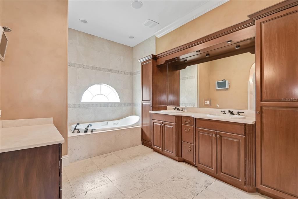 Primary bathroom features garden tub, separate shower and custom cabinetry