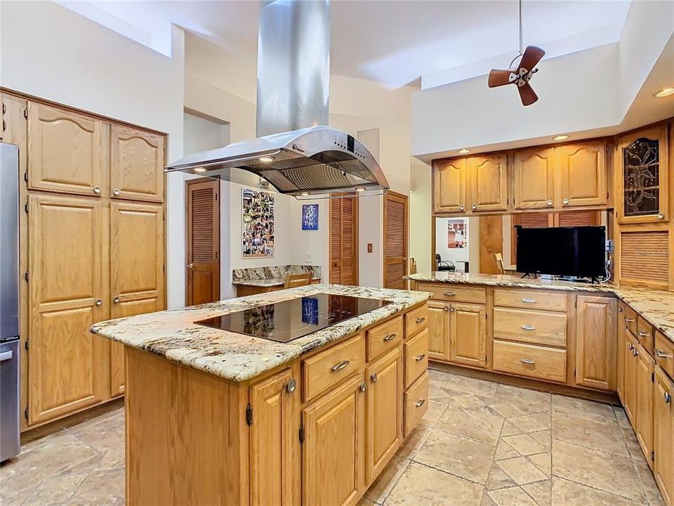 Large kitchen with smooth top stove and exhaust fan.