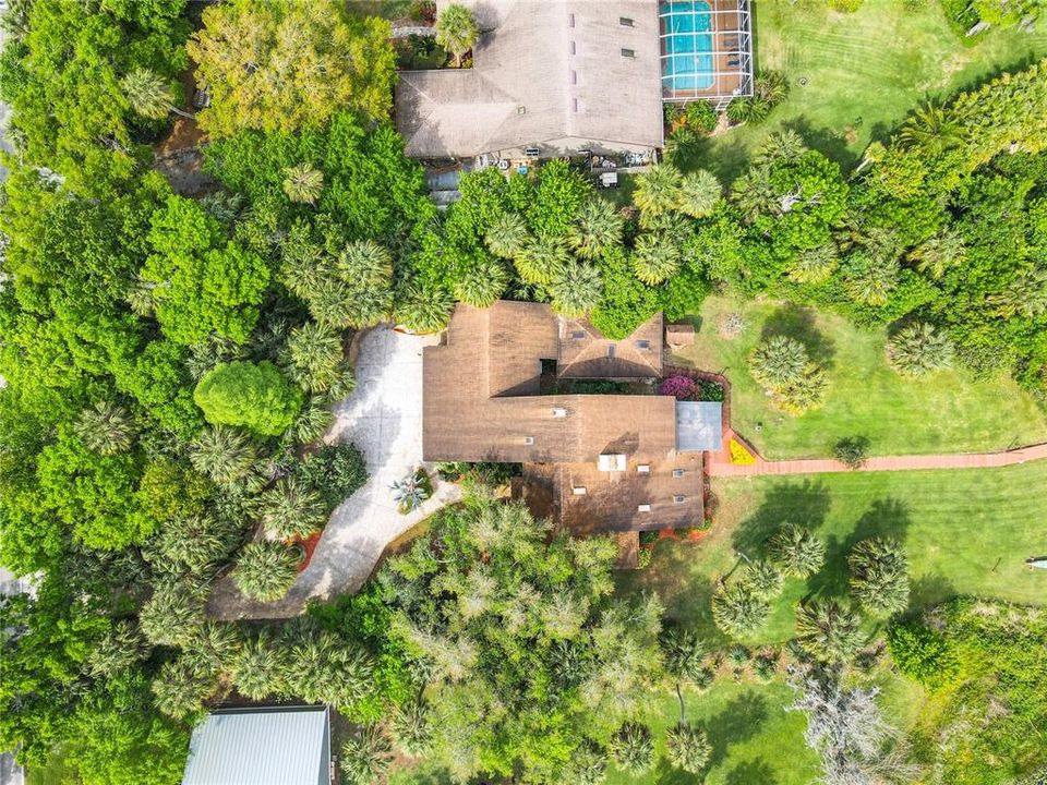 Aerial view of the entrance, circular driveway, home, dock, and mature landscaping that makes this lakefront retreat so peaceful and private.