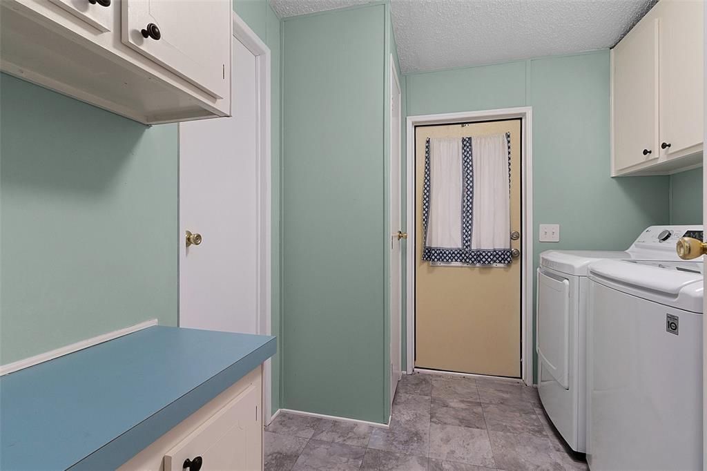 Interior laundry room with a storage closet and cabinetry