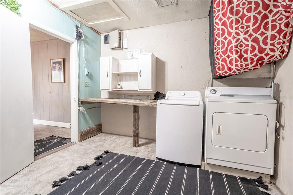 The laundty room has a built in folding table with cabinets above.