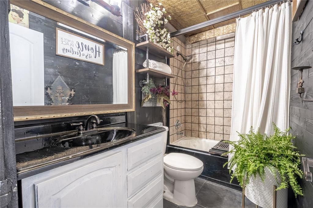 Bathroom two is oozes charm, with a mirrored vanity, and a tub with shower.