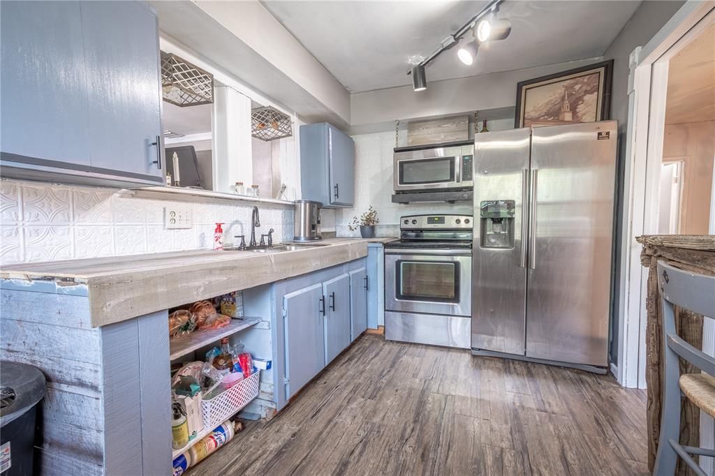 The kitchen features a stainless steel French door refrigerator with water dispenser and ice maker, a range and microwave.