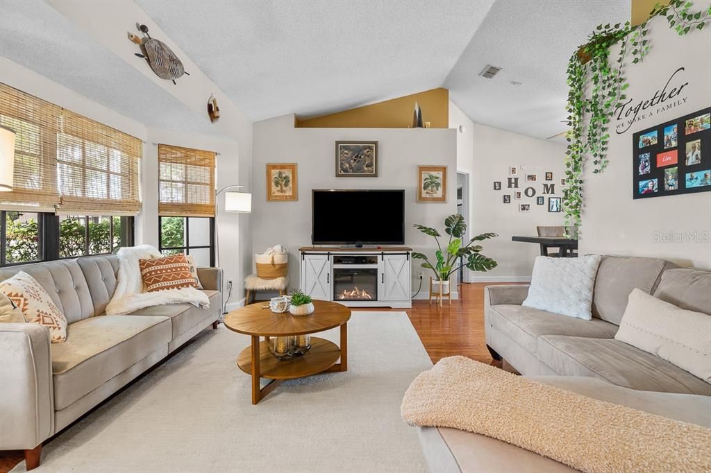 Cozy and welcoming family room with vaulted ceilings. The carpets hide these beautiful hardwood floors.